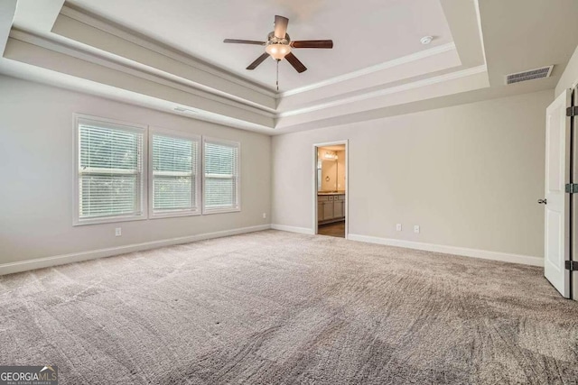 carpeted spare room with a raised ceiling, ornamental molding, and ceiling fan