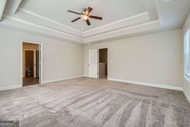 unfurnished bedroom with multiple windows, ceiling fan, carpet, and a raised ceiling