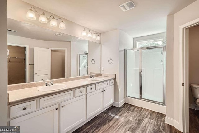 bathroom featuring walk in shower, hardwood / wood-style flooring, vanity, and toilet