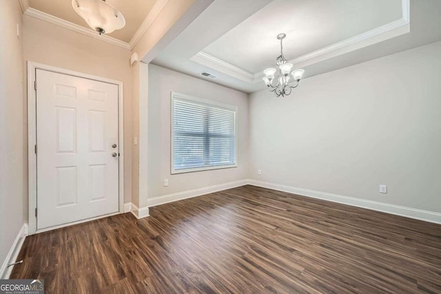 entryway with a raised ceiling, crown molding, dark wood-type flooring, and a chandelier