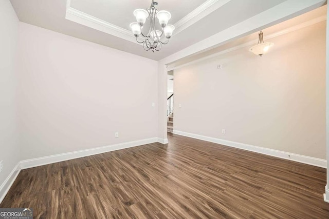 unfurnished room with dark wood-type flooring, ornamental molding, a tray ceiling, and a chandelier