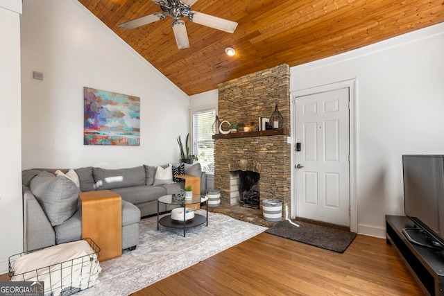 living room featuring lofted ceiling, wood ceiling, a fireplace, light hardwood / wood-style floors, and ceiling fan