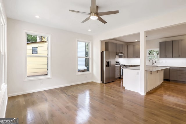 kitchen featuring a healthy amount of sunlight, stainless steel appliances, wood-type flooring, and an island with sink