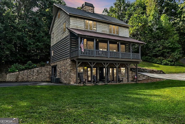 view of front facade featuring a lawn and central air condition unit