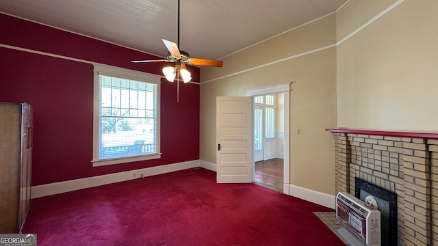 unfurnished living room featuring dark carpet, a brick fireplace, heating unit, and ceiling fan