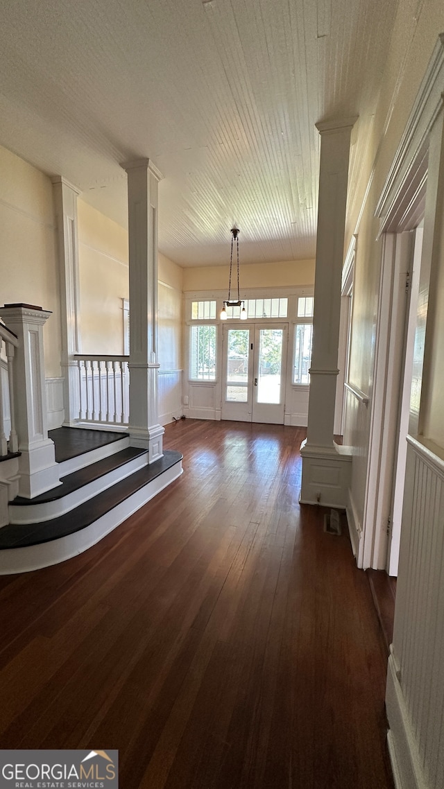 unfurnished living room with decorative columns and dark hardwood / wood-style floors