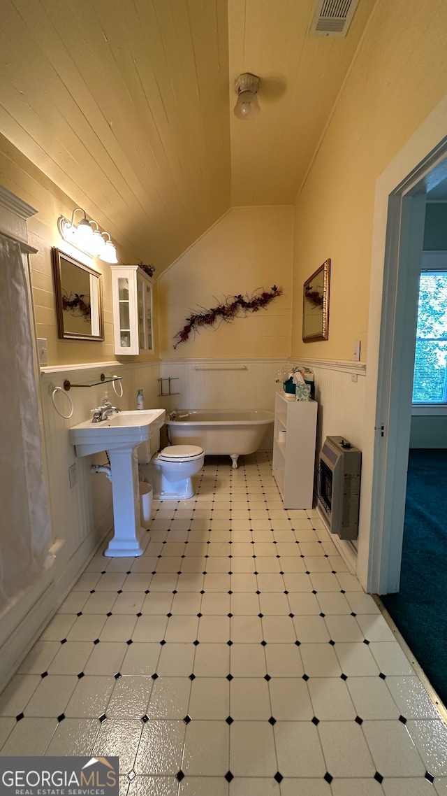 bathroom featuring toilet, lofted ceiling, heating unit, and a bath