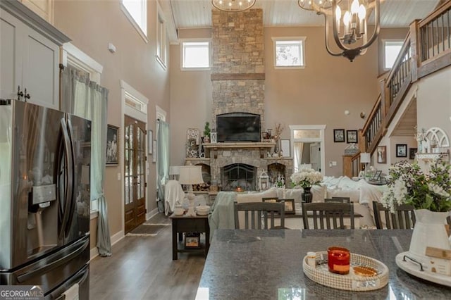 dining room featuring a towering ceiling, dark hardwood / wood-style floors, a fireplace, and a healthy amount of sunlight