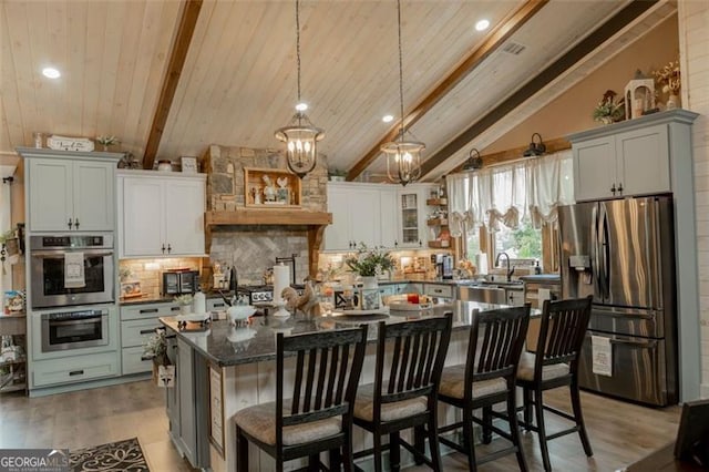 kitchen featuring lofted ceiling with beams, a center island, a kitchen breakfast bar, stainless steel appliances, and hardwood / wood-style flooring