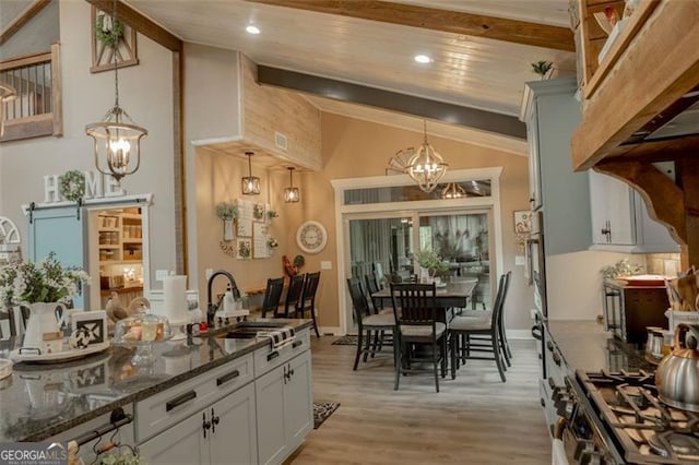 kitchen with sink, pendant lighting, a barn door, and white cabinets