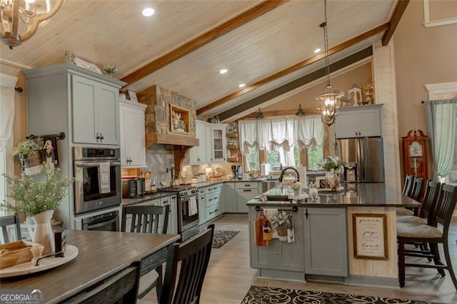 kitchen with vaulted ceiling with beams, a center island, decorative light fixtures, appliances with stainless steel finishes, and tasteful backsplash