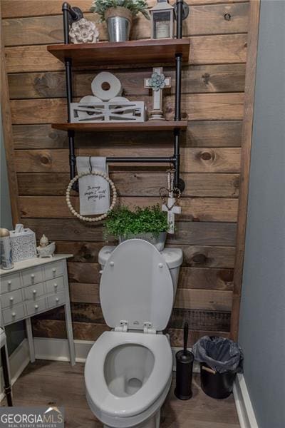 bathroom featuring wood-type flooring, toilet, and wood walls