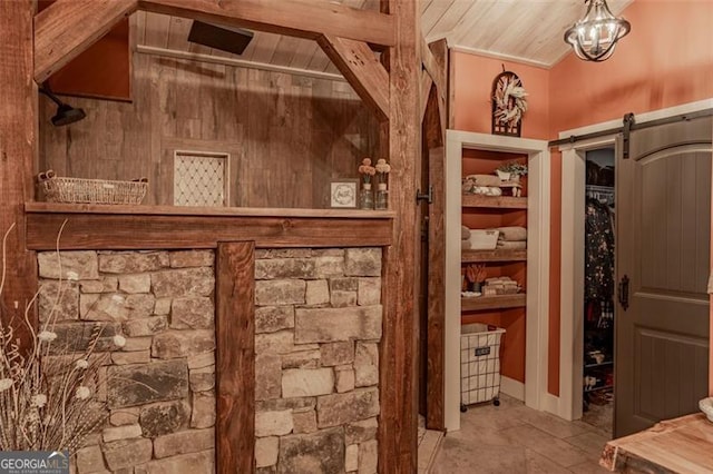 wine cellar with wood ceiling, ornamental molding, vaulted ceiling, and a barn door