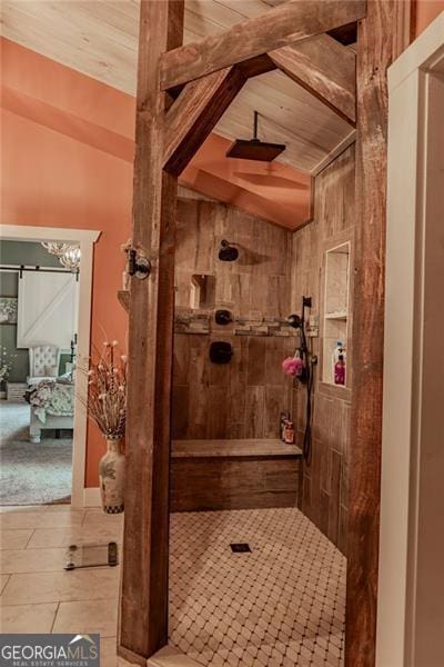 bathroom with a tile shower, wooden ceiling, vaulted ceiling, and tile patterned flooring