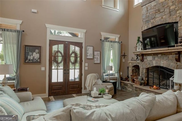 living room featuring french doors, hardwood / wood-style flooring, a fireplace, and a wealth of natural light