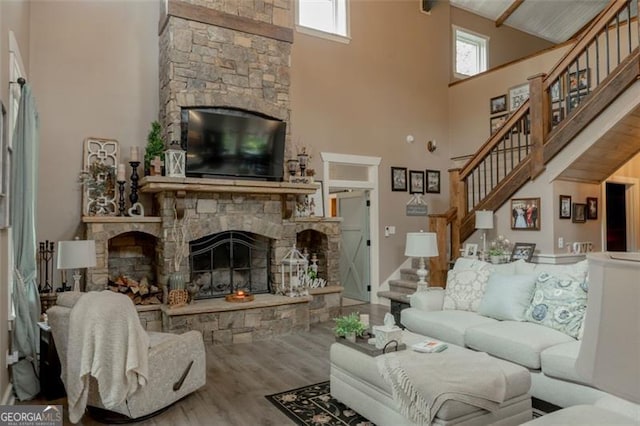 living room featuring hardwood / wood-style floors, a stone fireplace, and high vaulted ceiling