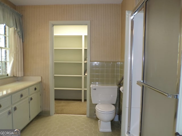 bathroom with tile patterned flooring, a shower with shower door, vanity, and toilet