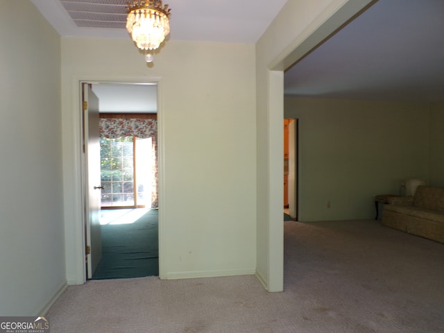 carpeted empty room with a chandelier