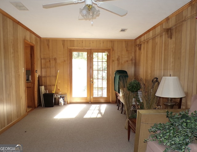 sitting room with ceiling fan, wood walls, french doors, and carpet