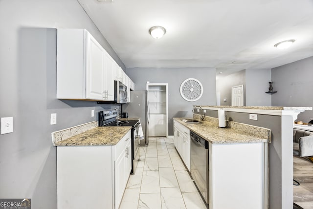 kitchen featuring white cabinets, stainless steel appliances, sink, and light stone countertops