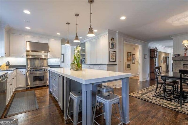 kitchen with dark wood-type flooring, white cabinetry, decorative light fixtures, and a breakfast bar