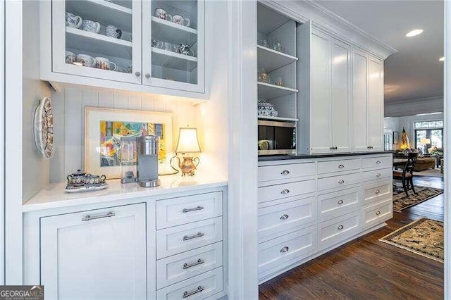 bar with ornamental molding, white cabinetry, and dark hardwood / wood-style floors