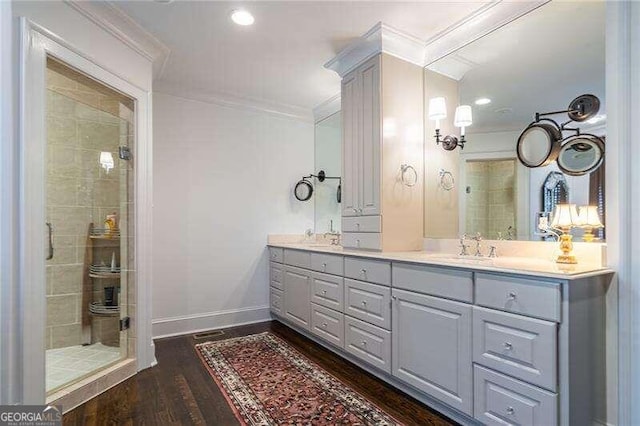 bathroom with wood-type flooring, vanity, crown molding, and a tile shower