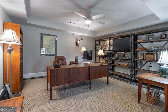 home office with a tray ceiling and ceiling fan