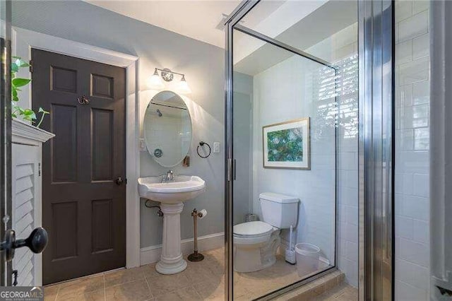 bathroom featuring toilet, an enclosed shower, and tile patterned floors