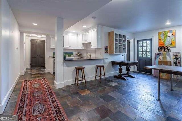 kitchen featuring sink, a kitchen breakfast bar, kitchen peninsula, and white cabinetry