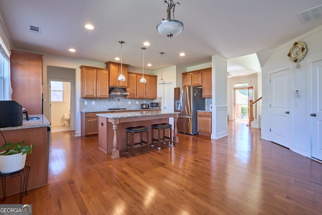 kitchen with light stone countertops, stainless steel appliances, dark hardwood / wood-style flooring, and a healthy amount of sunlight