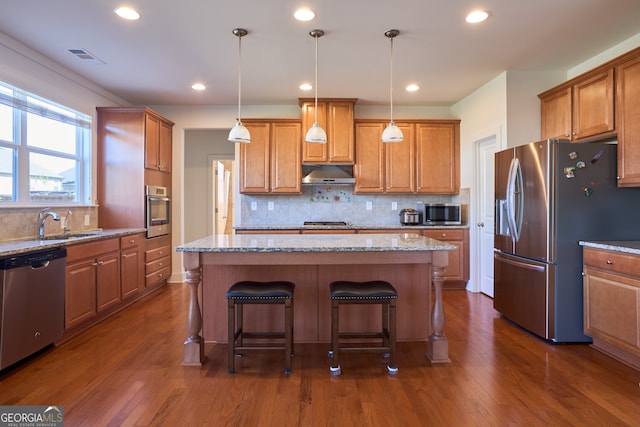 kitchen with appliances with stainless steel finishes, dark wood-type flooring, and a center island