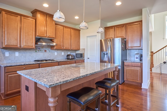 kitchen featuring pendant lighting, tasteful backsplash, dark wood-type flooring, stainless steel appliances, and a center island