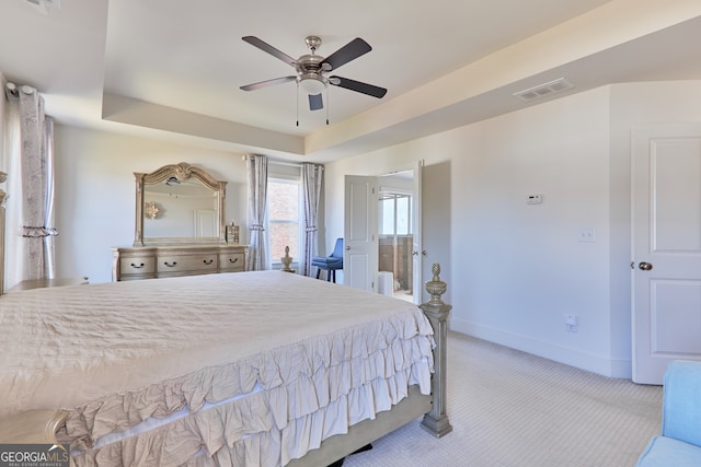 bedroom with light carpet, ceiling fan, and a tray ceiling