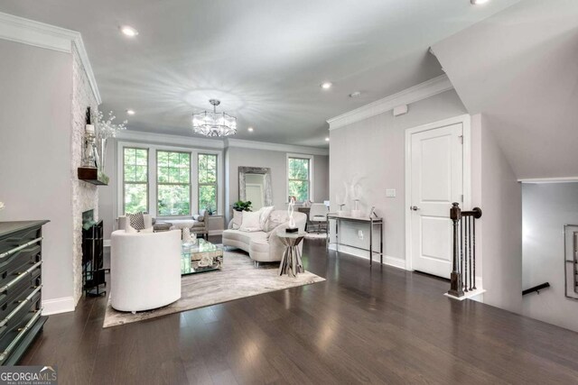 living room featuring dark wood-type flooring, a notable chandelier, crown molding, and a fireplace