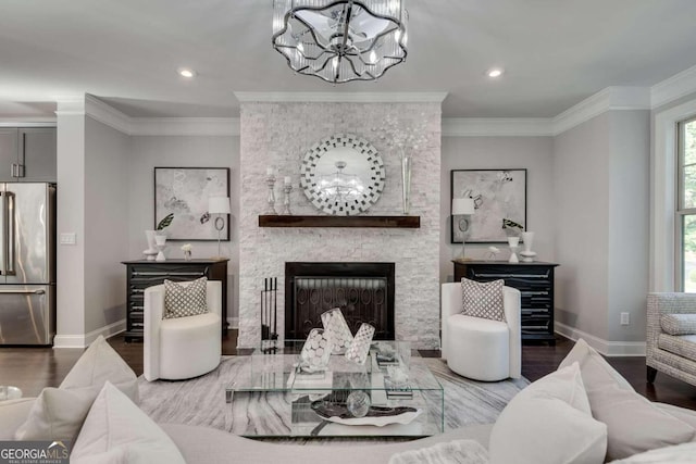 living room featuring hardwood / wood-style flooring, a fireplace, a chandelier, and ornamental molding