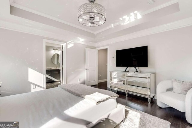 bedroom with dark hardwood / wood-style floors, a tray ceiling, ensuite bathroom, and ornamental molding