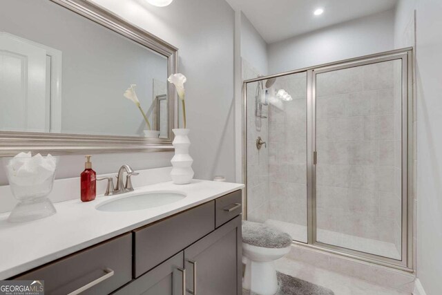 bathroom with toilet, a shower with door, and vanity