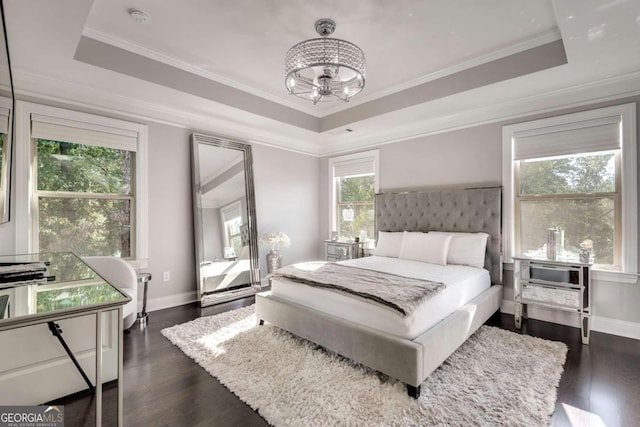 bedroom featuring a tray ceiling, dark hardwood / wood-style floors, ornamental molding, and multiple windows