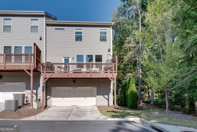 exterior space with a garage, cooling unit, and a wooden deck