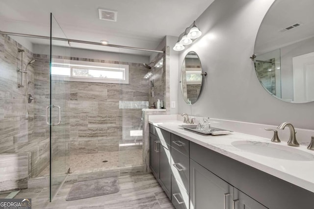 bathroom featuring a shower with door and vanity