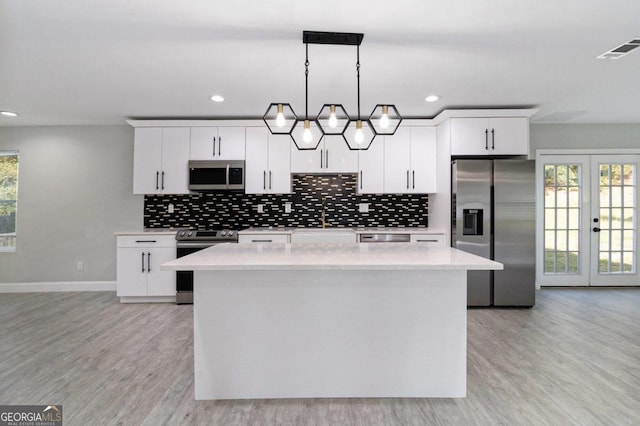 kitchen featuring appliances with stainless steel finishes, decorative light fixtures, and white cabinets