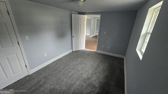 unfurnished bedroom with dark carpet