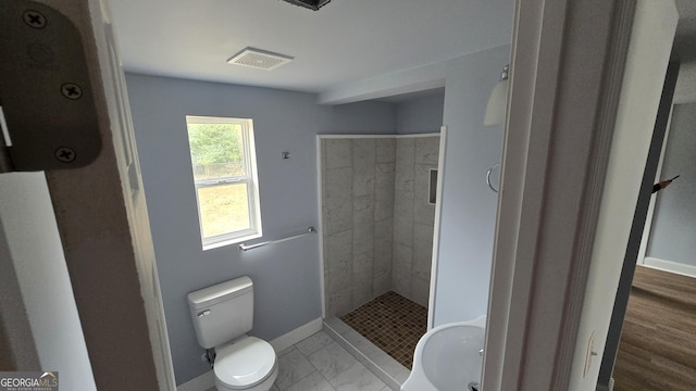 bathroom with a tile shower, toilet, and hardwood / wood-style floors