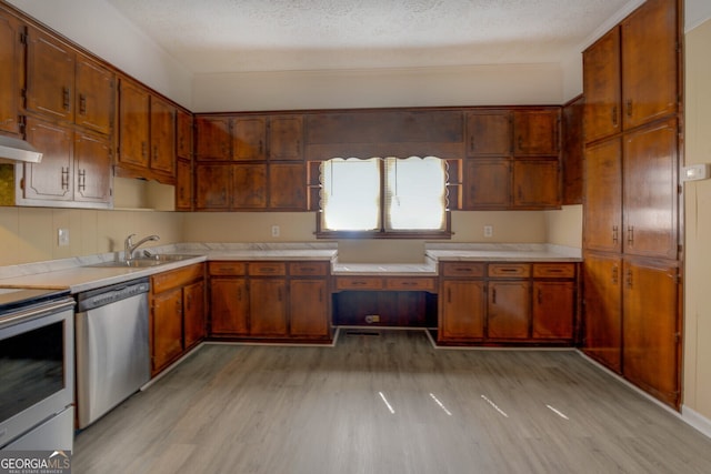 kitchen with light hardwood / wood-style flooring, a textured ceiling, stainless steel appliances, and sink