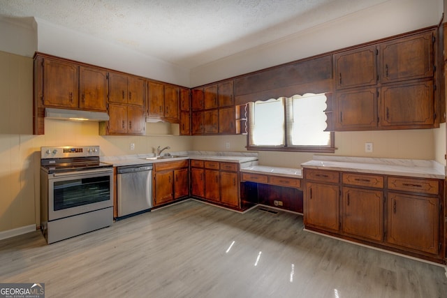 kitchen featuring sink, a textured ceiling, stainless steel appliances, and light wood-type flooring