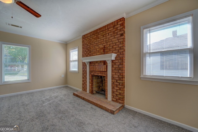 unfurnished living room with ornamental molding, ceiling fan, light colored carpet, and a brick fireplace