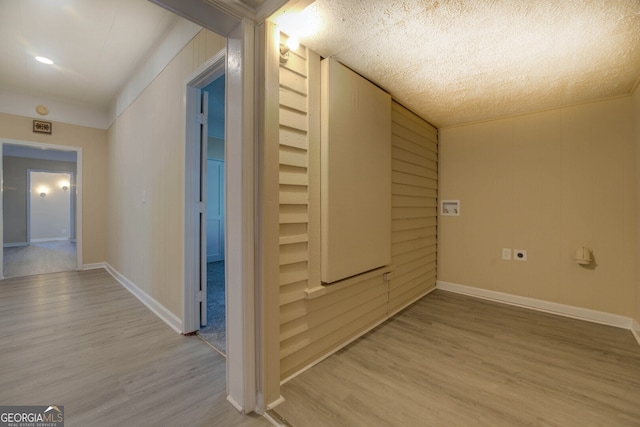 hallway with a textured ceiling and light wood-type flooring