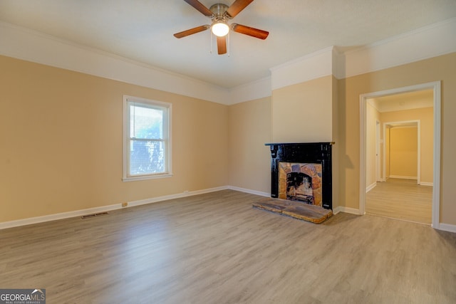 unfurnished living room with light hardwood / wood-style floors, ornamental molding, a fireplace, and ceiling fan