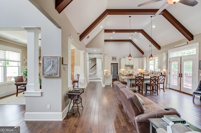 living room with hardwood / wood-style floors, high vaulted ceiling, plenty of natural light, and decorative columns